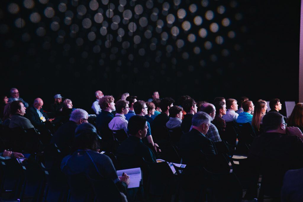 Menschenmenge in einem Konferenzraum, die sich auf ein spannendes Event im Bereich IT konzentriert.